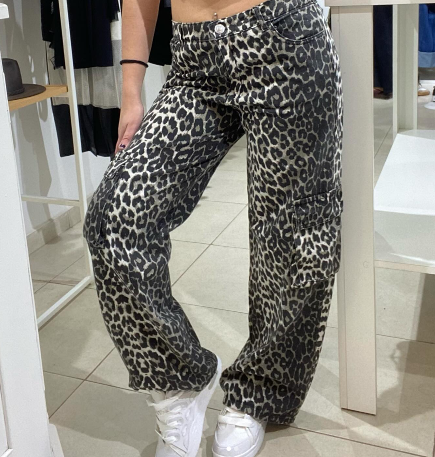 Mujer con pantalones con estampado de leopardo y zapatillas blancas en una tienda.