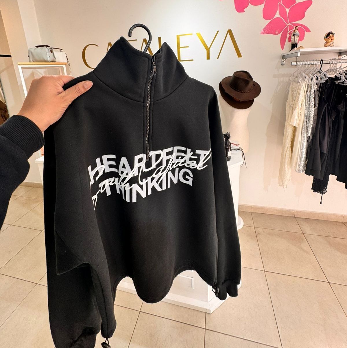 Sudadera negra con texto blanco “HEARTFELT THINKING” conservada en una boutique.