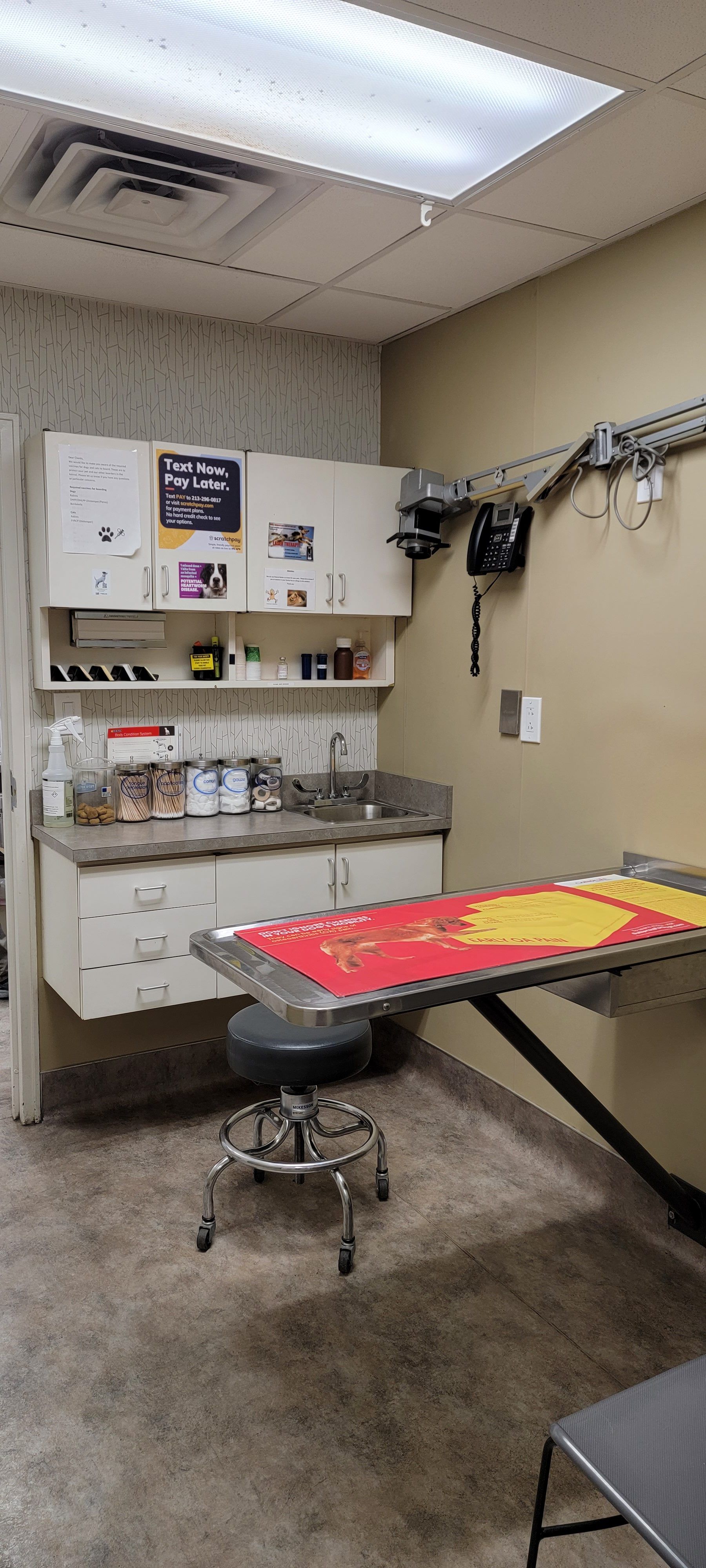 A veterinarian 's office with a table and a stool.