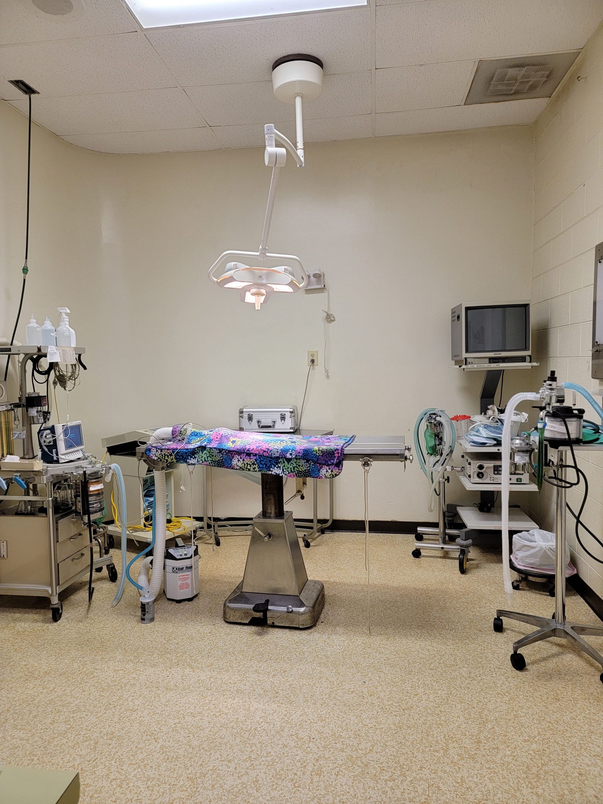An empty operating room with a table and a television.