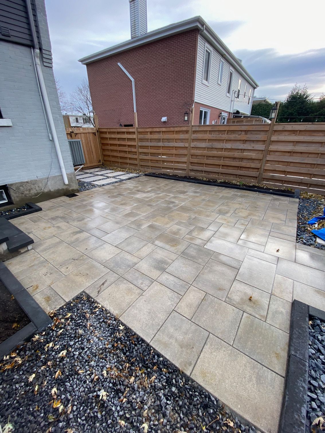 Un patio avec une clôture en bois et un bâtiment en briques en arrière-plan.