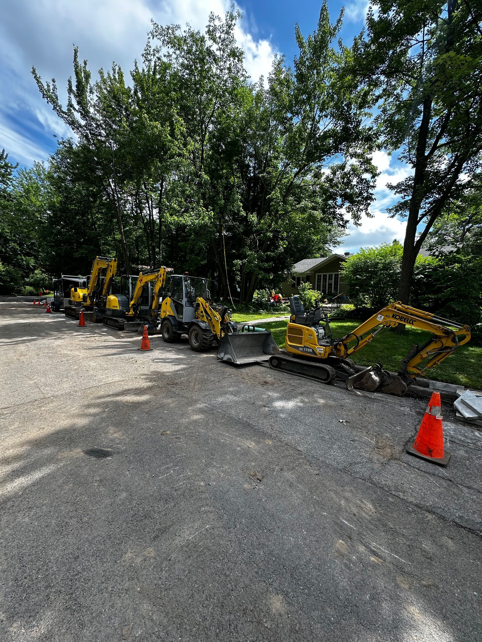Une rangée de véhicules de construction est garée sur un terrain en gravier.