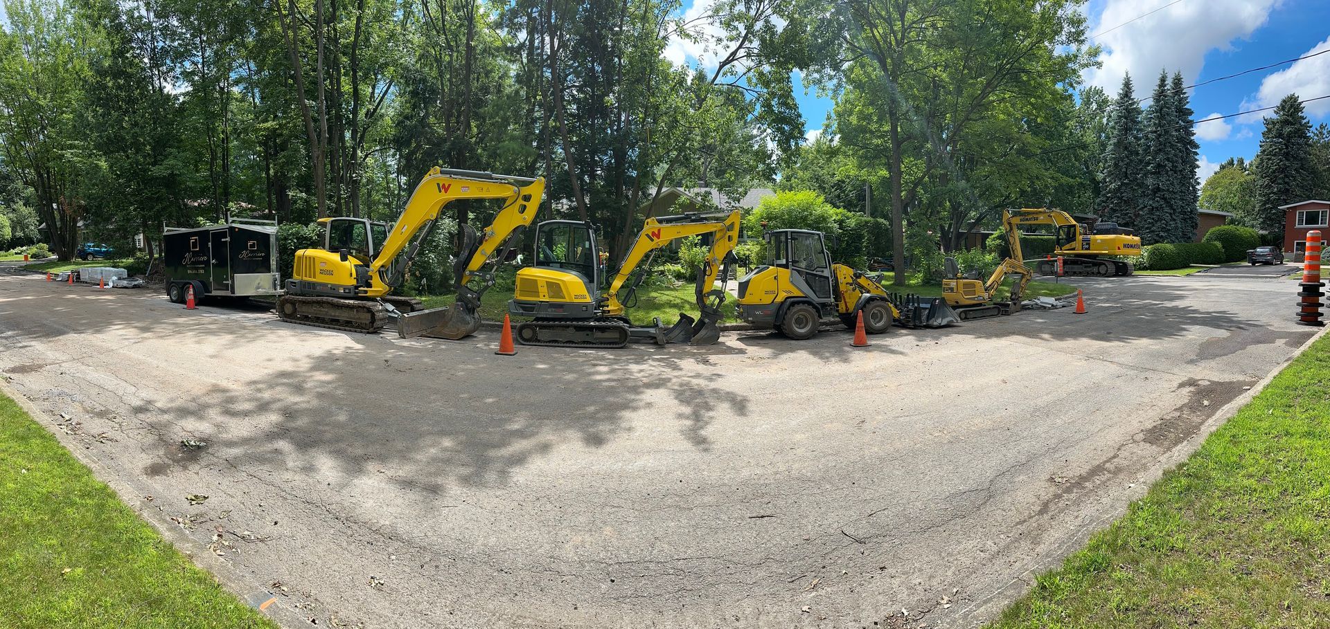 Un groupe de véhicules de construction jaunes est garé sur un terrain en gravier.
