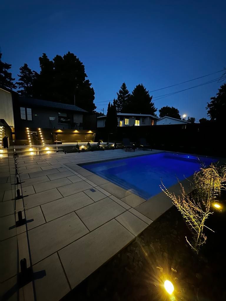 Une grande piscine est éclairée la nuit.