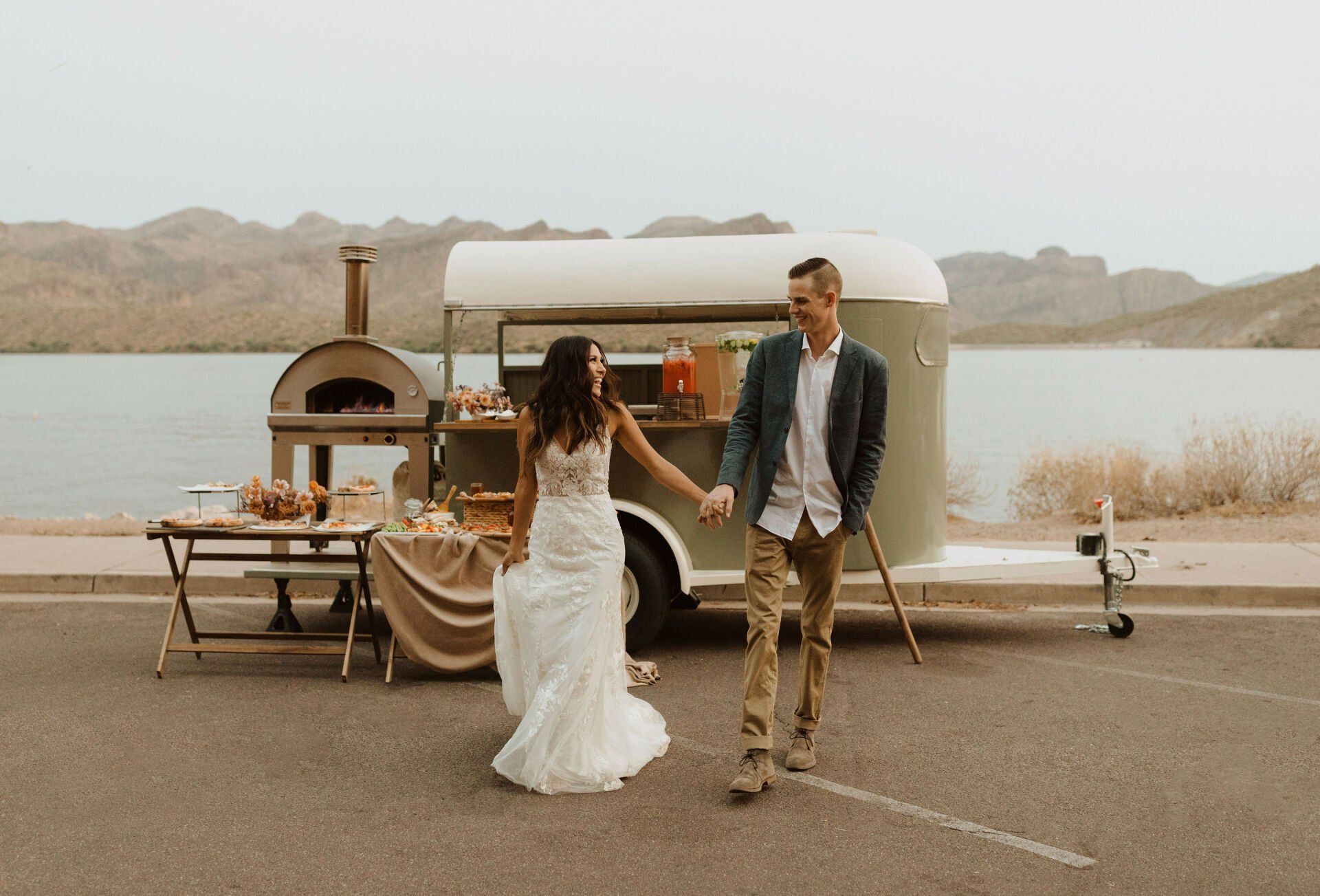 A bride and groom are holding hands in front of Beyond Basil Mobile Pizzeria.