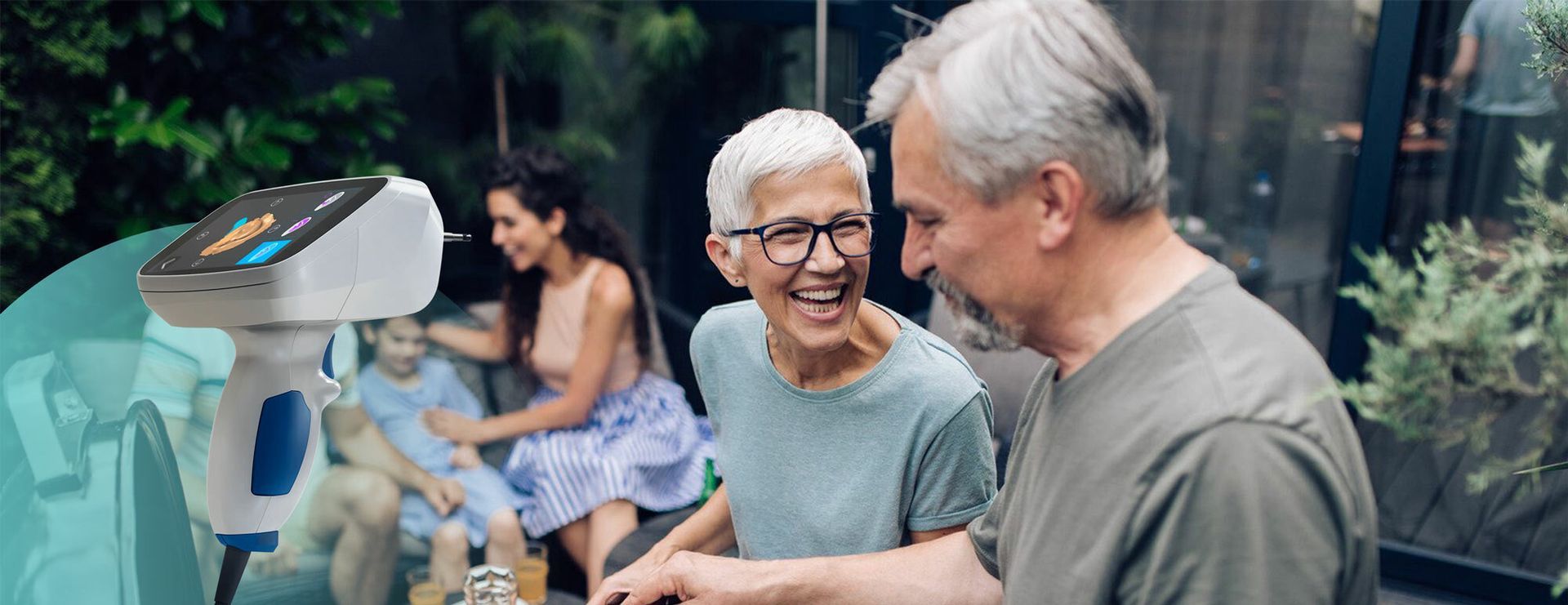 Older couple smiling outdoors with an audiology device in focus.