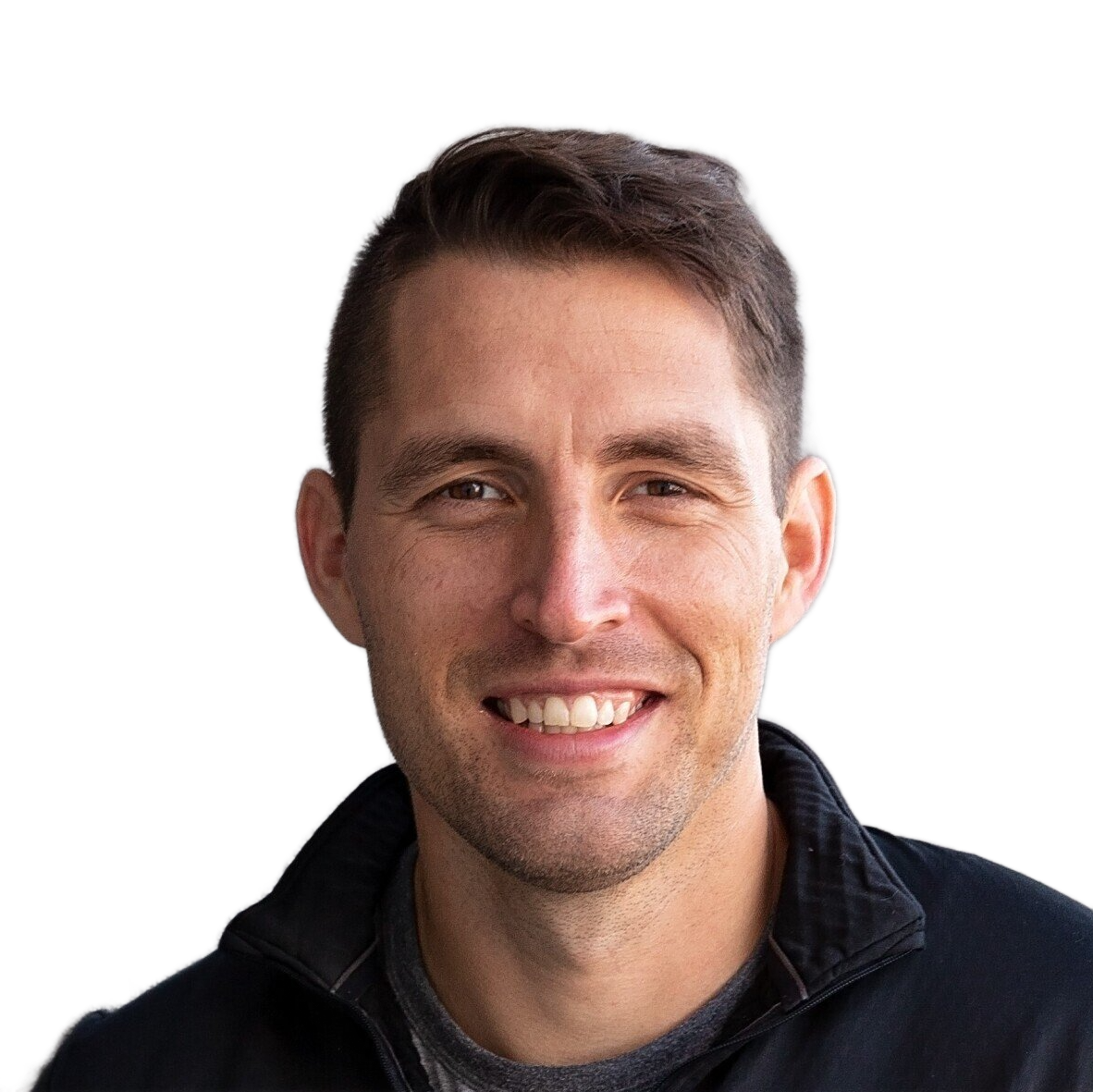 A man is smiling for the camera while standing in front of a wall.