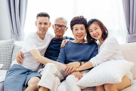 Smiling multigenerational family sitting together, embracing on a couch.