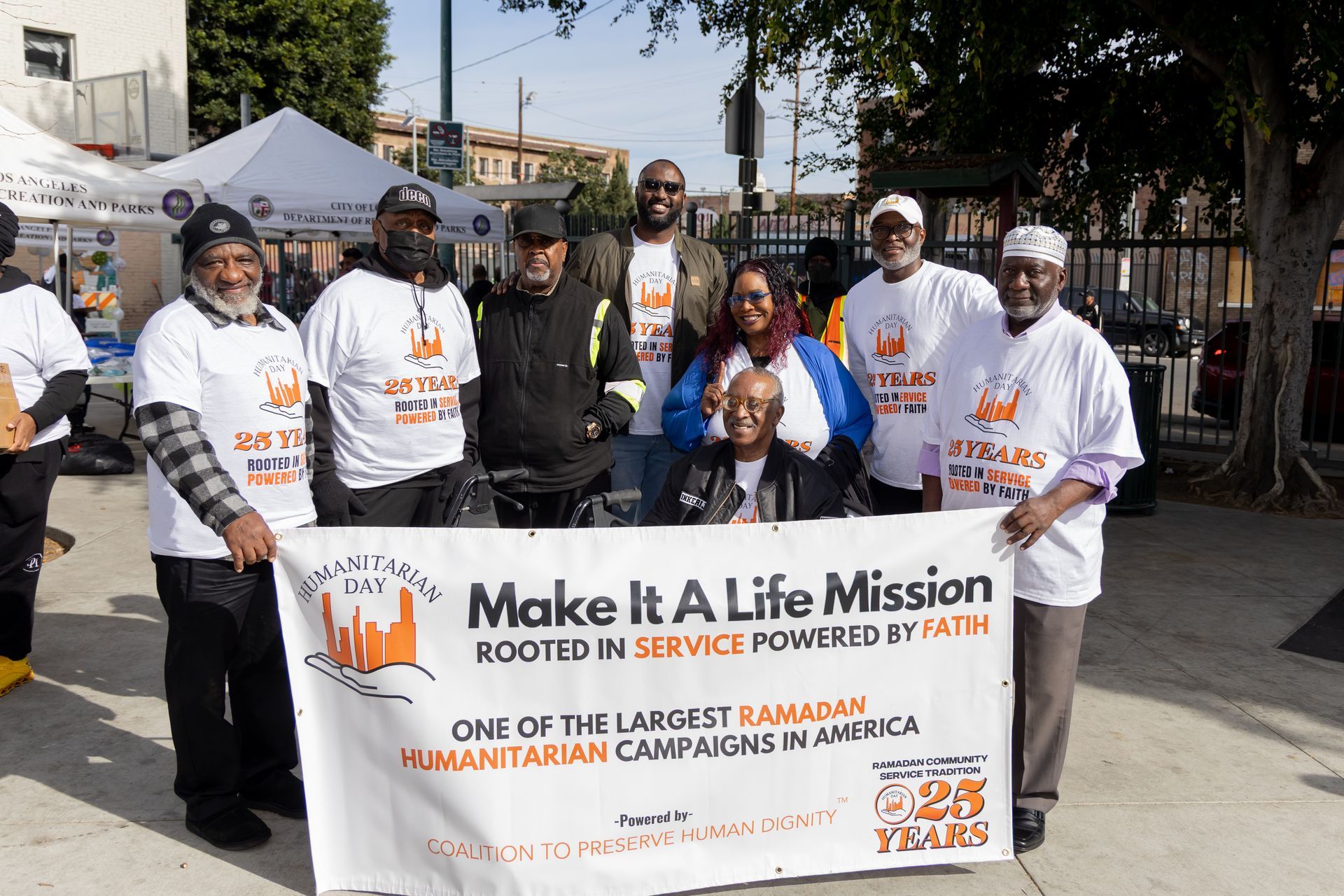 Group of people holding a banner for a humanitarian campaign, outdoors.