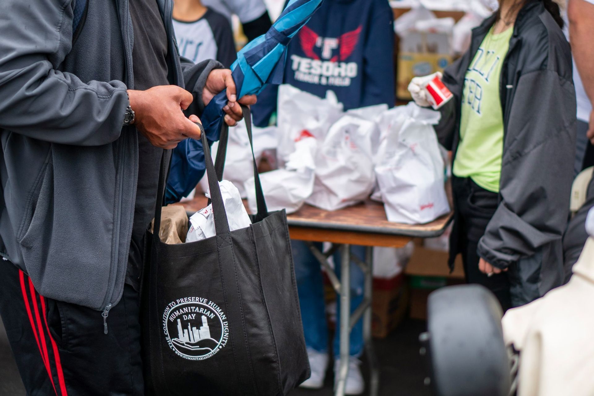 A group of people are standing around a table holding bags.