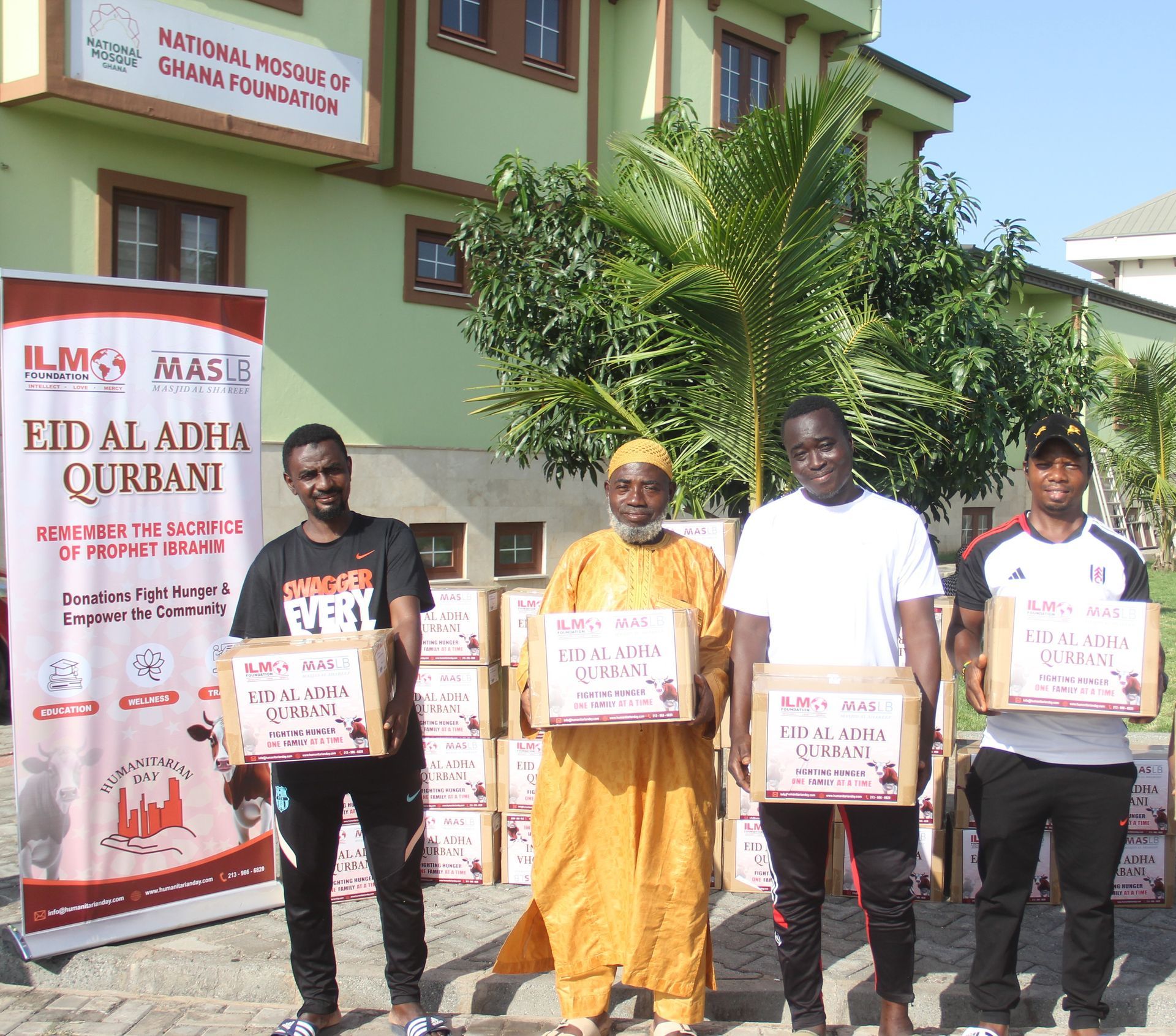 A group of men standing in front of a sign that says eid al adha qurban