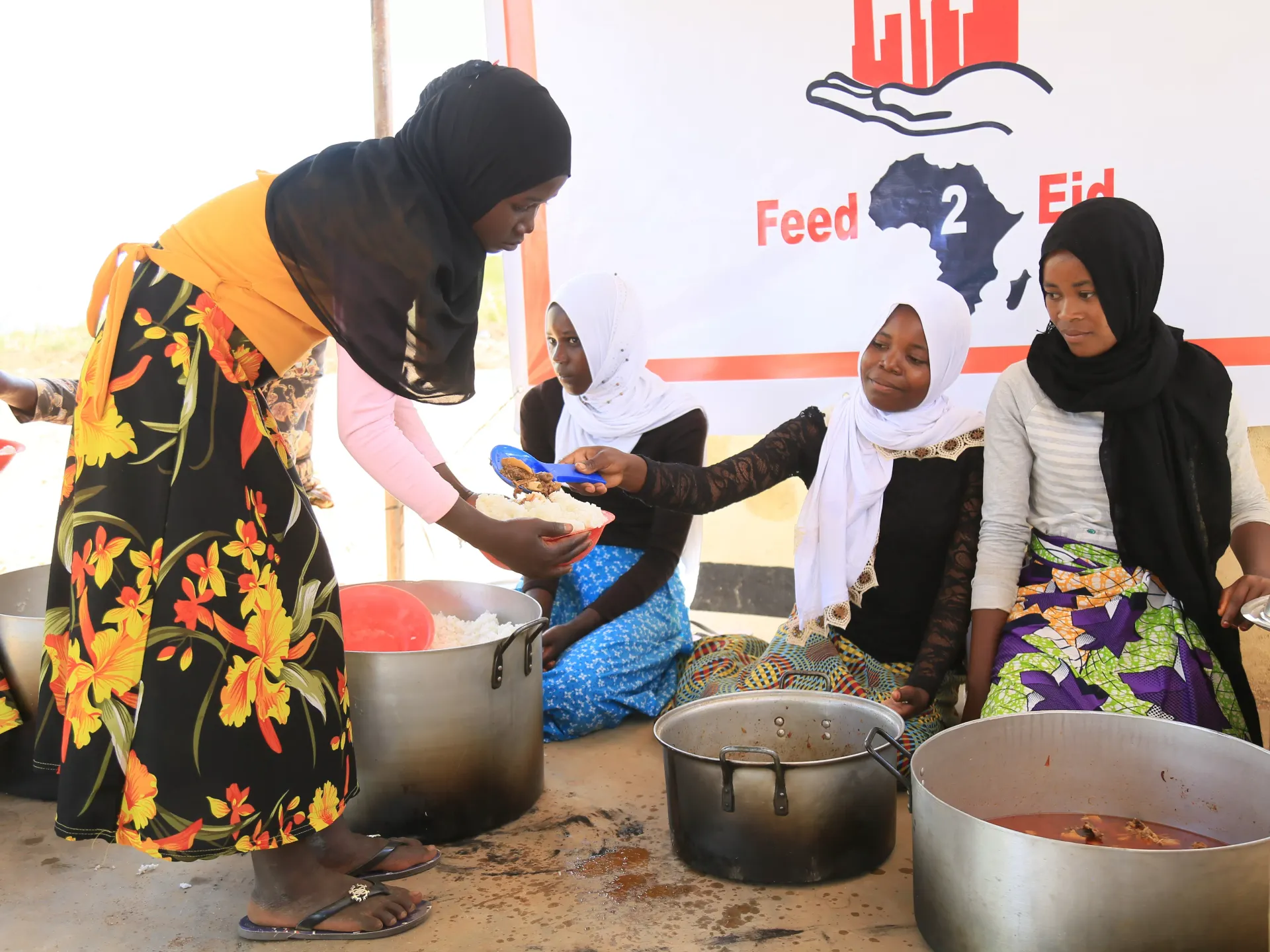 Women preparing and serving food in an outdoor setting; charity event.