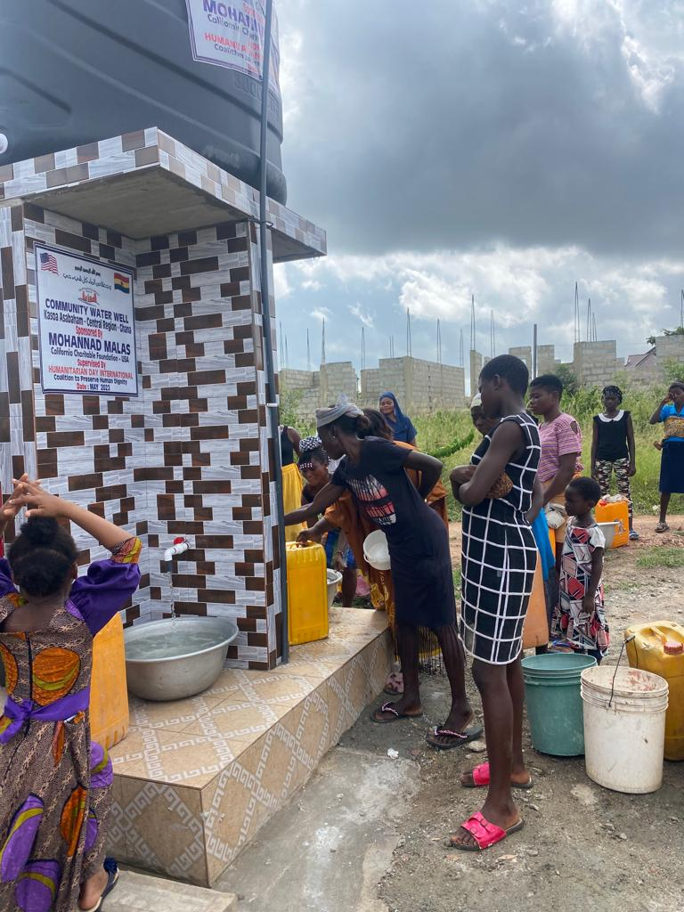 A group of people are standing around a water tank.
