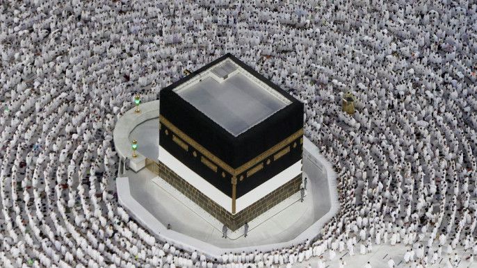 A large group of people are gathered around a building called the kaaba