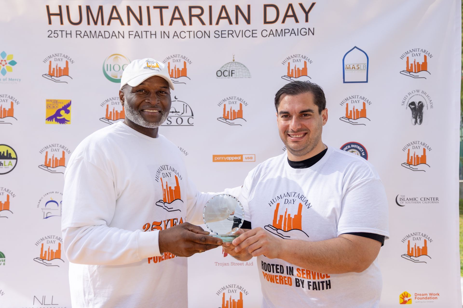 Two men shaking hands in front of a banner that says humanitarian day