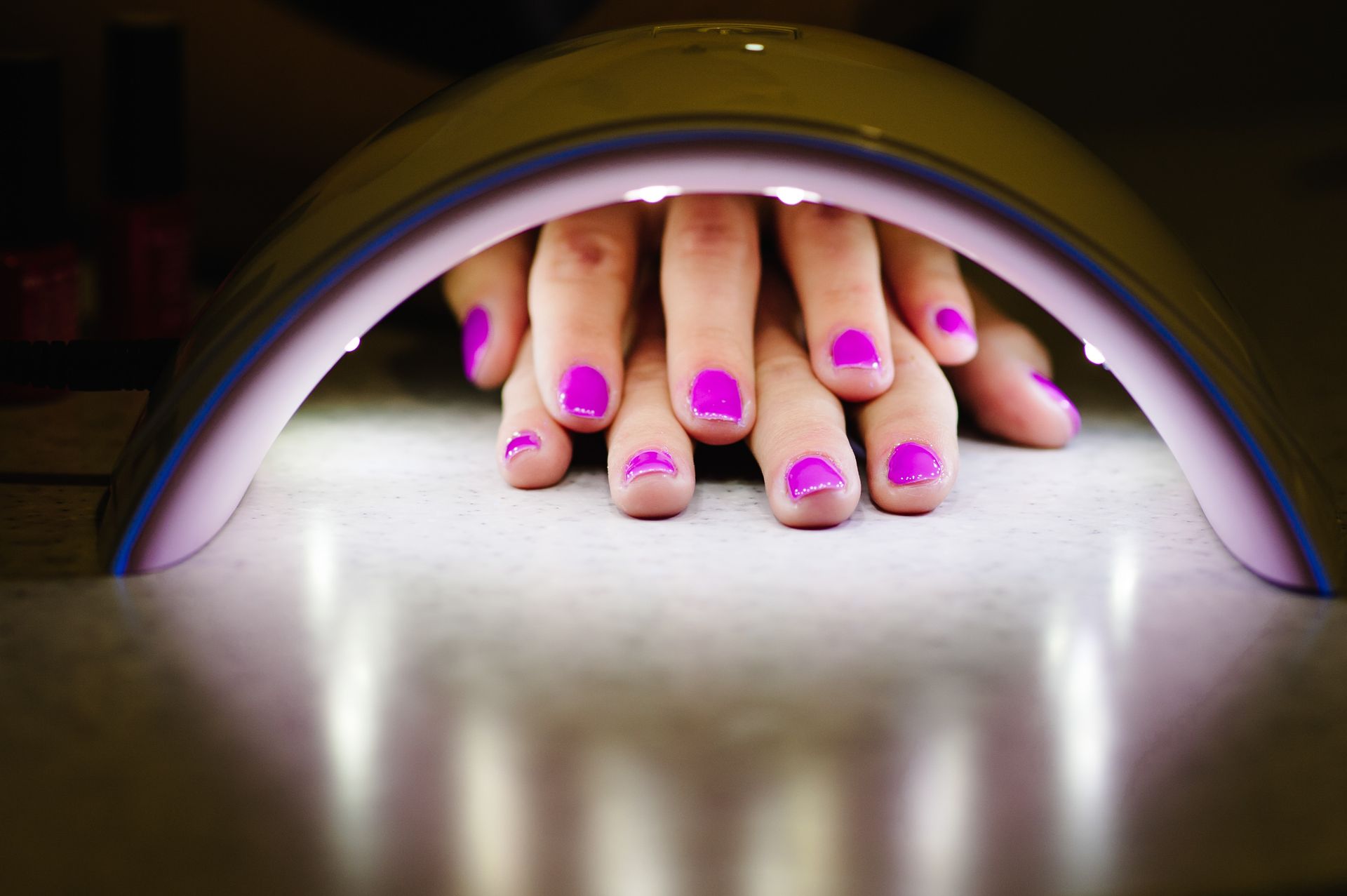A woman 's nails are being dried in a nail dryer.