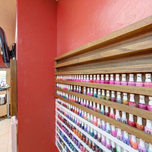 A shelf filled with lots of nail polish in a nail salon.