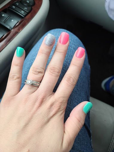 A woman 's hand with colorful nails and a ring on her finger.