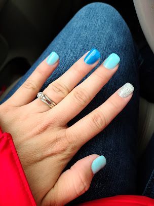 A woman 's hand with blue and white nails and a ring on her finger