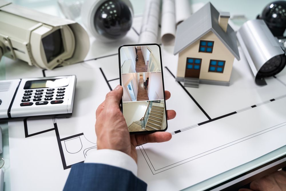 A Person is Holding a Cell Phone With a Picture of a House on It — Cambush Security Solutions NT in Palmerston, NT