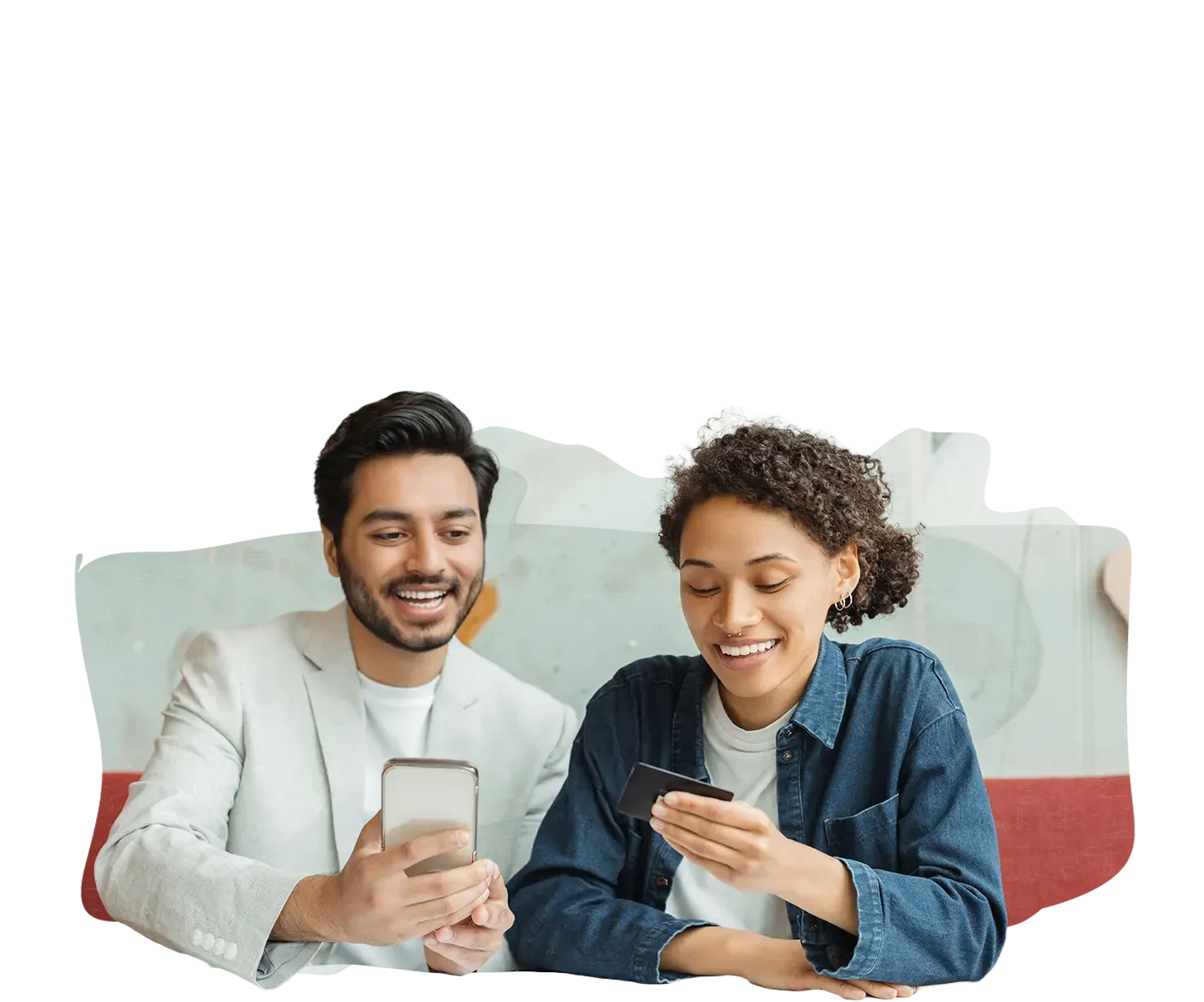 Man and woman looking at phones, smiling. Indoors, neutral background.