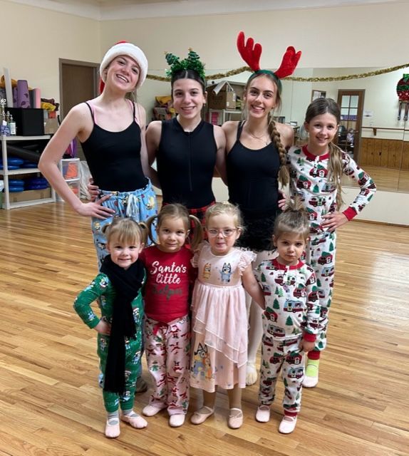 A group of dancers in pajamas and festive headwear posing in a dance studio.