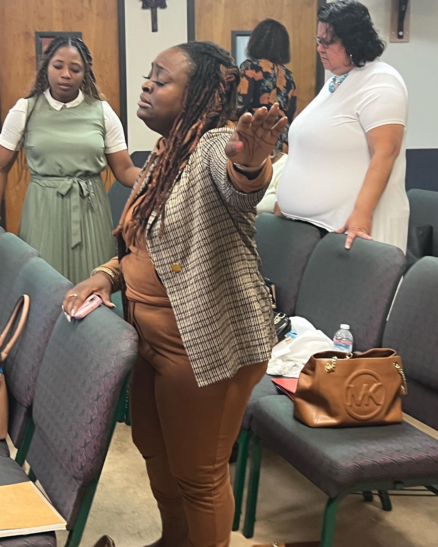 A woman is standing in a row of chairs in a church.