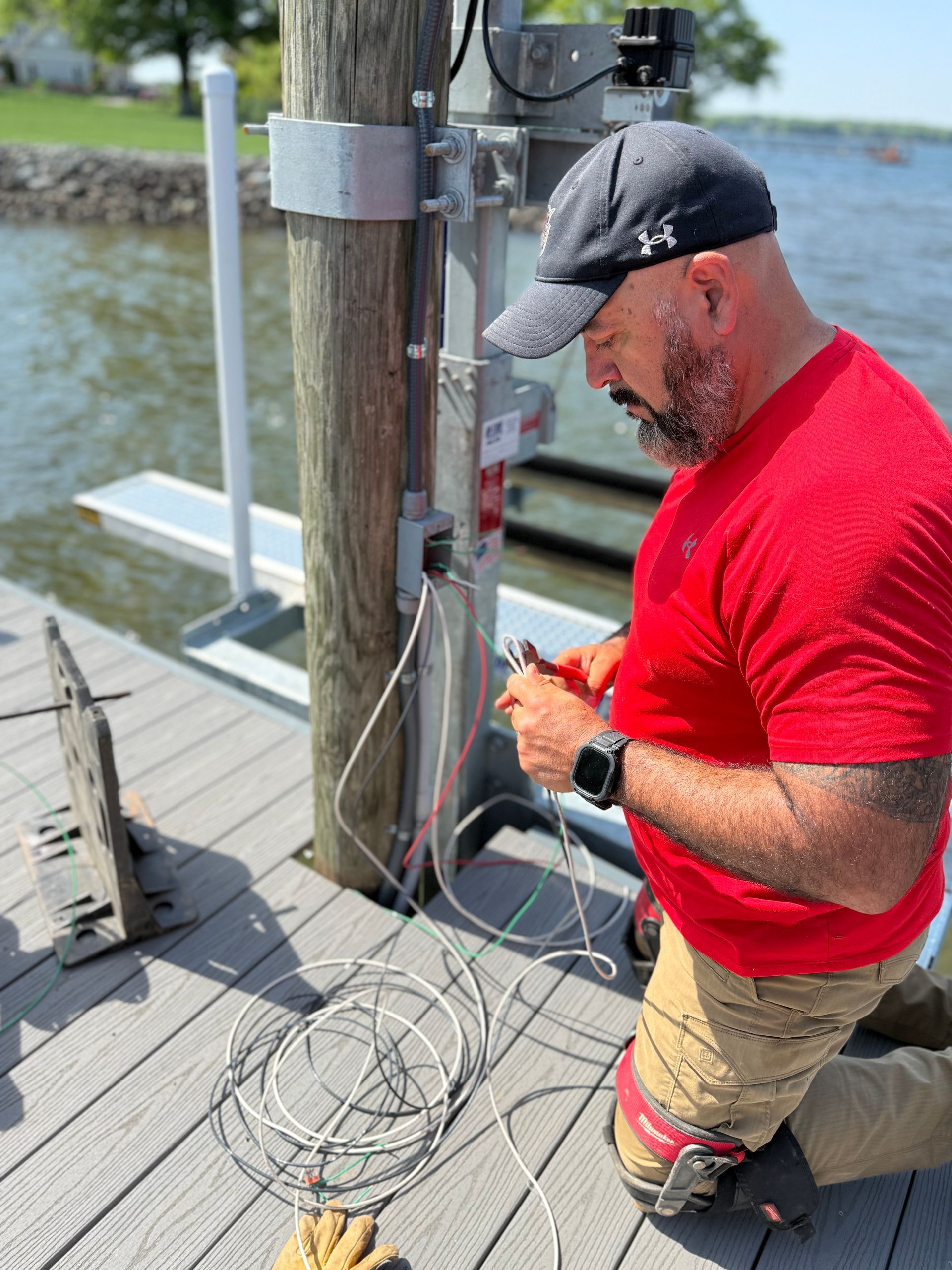 Electrician in an orange hard hat works on electrical panel.