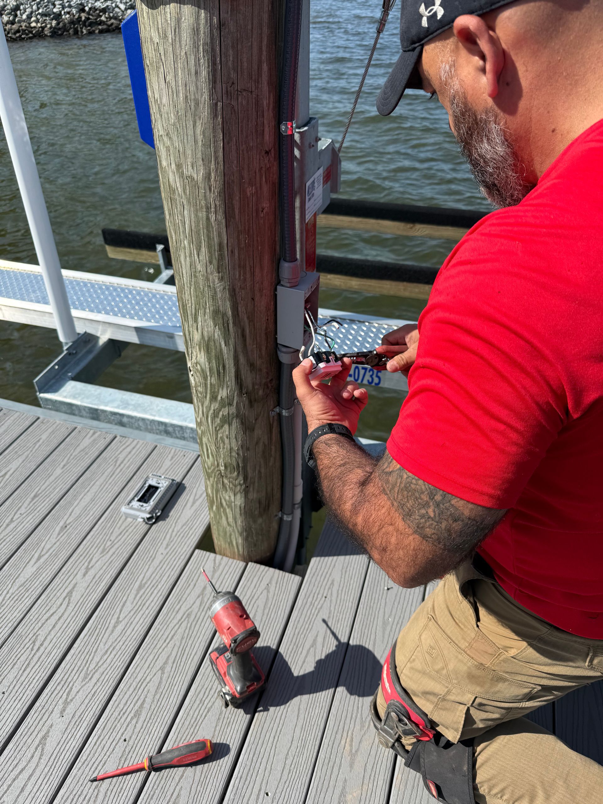 Electrician in hard hat and safety glasses working on wiring, interior construction site.