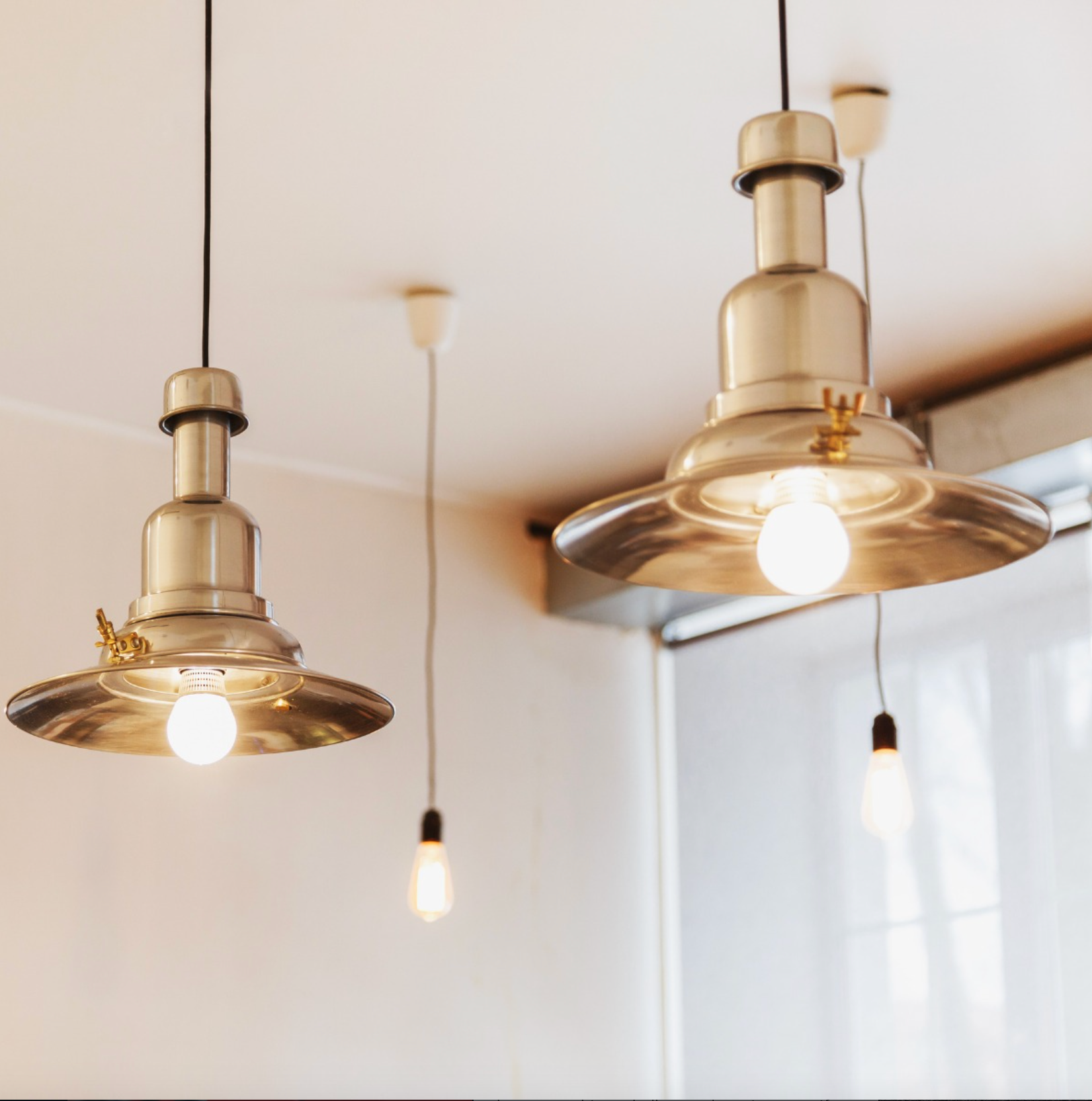Electrician with hard hat and headlamp, working on electrical panel.