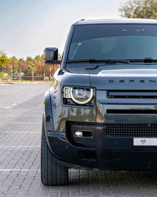 A black land rover defender is parked in a parking lot.