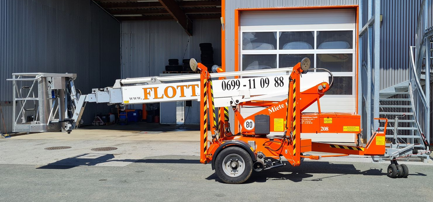 Ein orange-weißer Gabelstapleranhänger parkte vor einem Gebäude.
