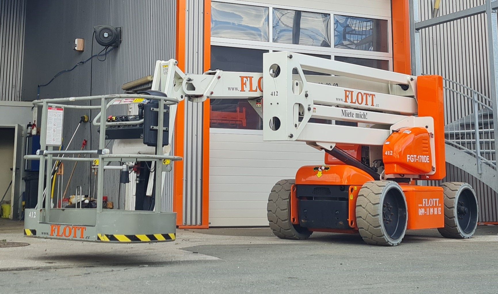 Orange-weiße Seilbahn vor einem Gebäude mit geschlossenem Garagentor.