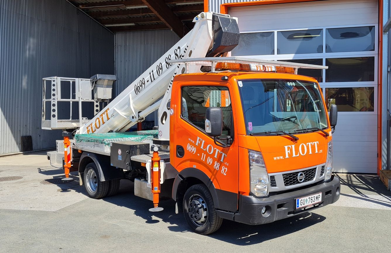 Oranger LKW mit Hubarbeitsbühne. „FLOTT“-Logo an der Seite. Geparkt vor einem Gebäude.