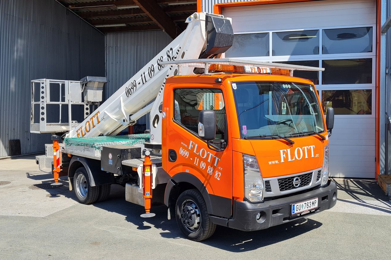 Ein orangefarbener FLOTT-LKW mit ausgefahrener Hubarbeitsbühne steht vor einem Gebäude mit geöffnetem Garagentor.