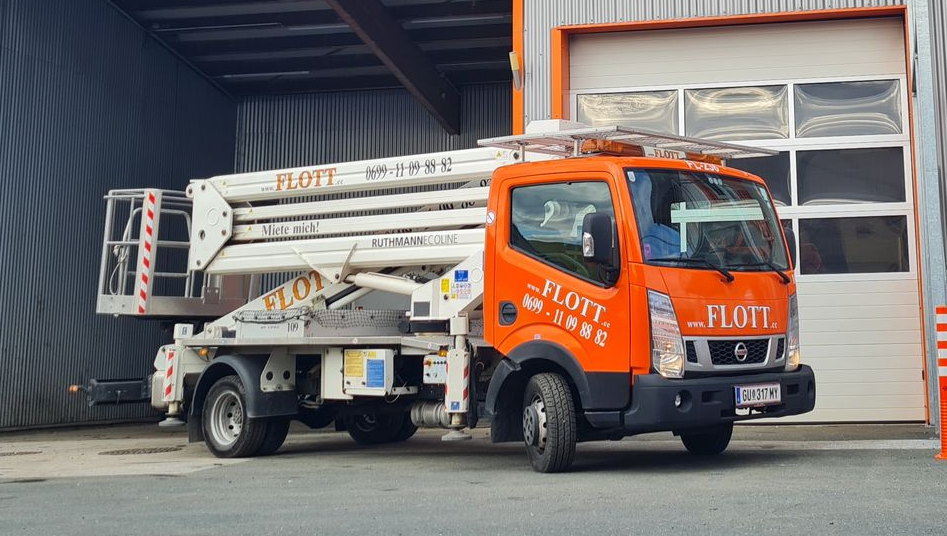 Ein orange-weißer FLOTT-Gabelstapler vor einem geschlossenen Garagentor.