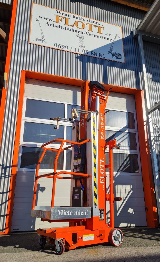 Orangefarbene Hebebühne vor einem Gebäude mit Firmenschild.