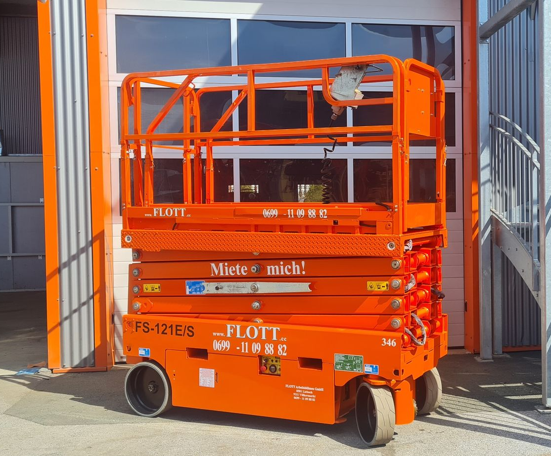 Eine orangefarbene Scherenhebebühne vor einem Gebäude mit geschlossenem Garagentor.