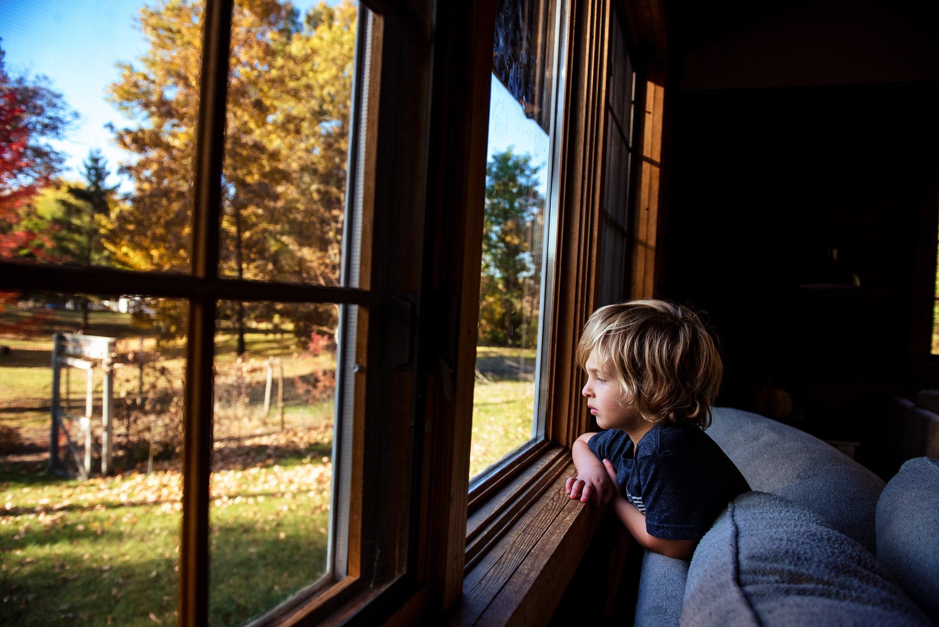 A young boy is looking out of a window.
