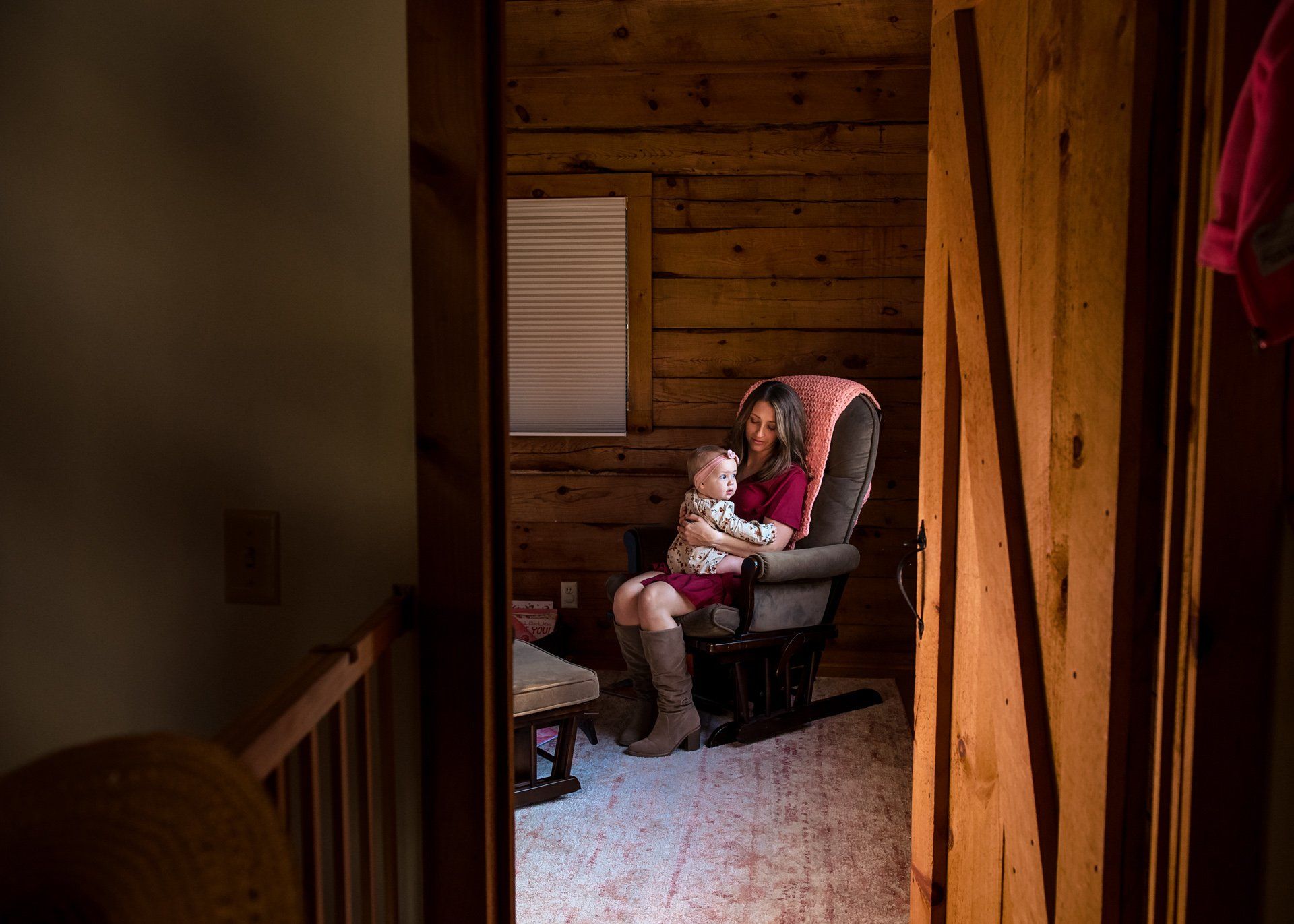 A woman is sitting in a rocking chair holding a baby.