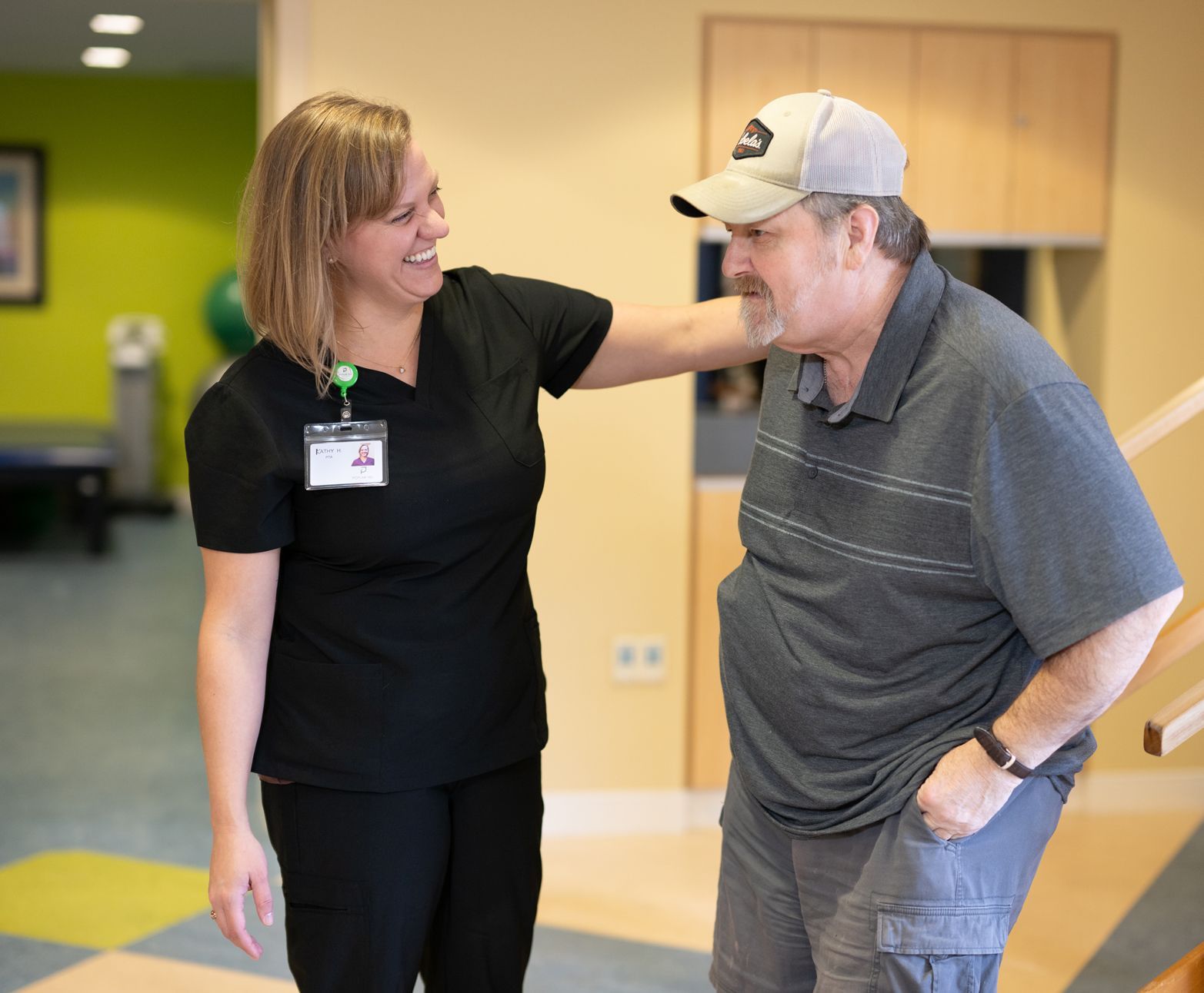 A woman is talking to a man in a baseball cap.