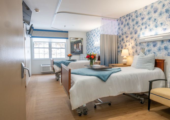 A hospital room with two beds and a chair.