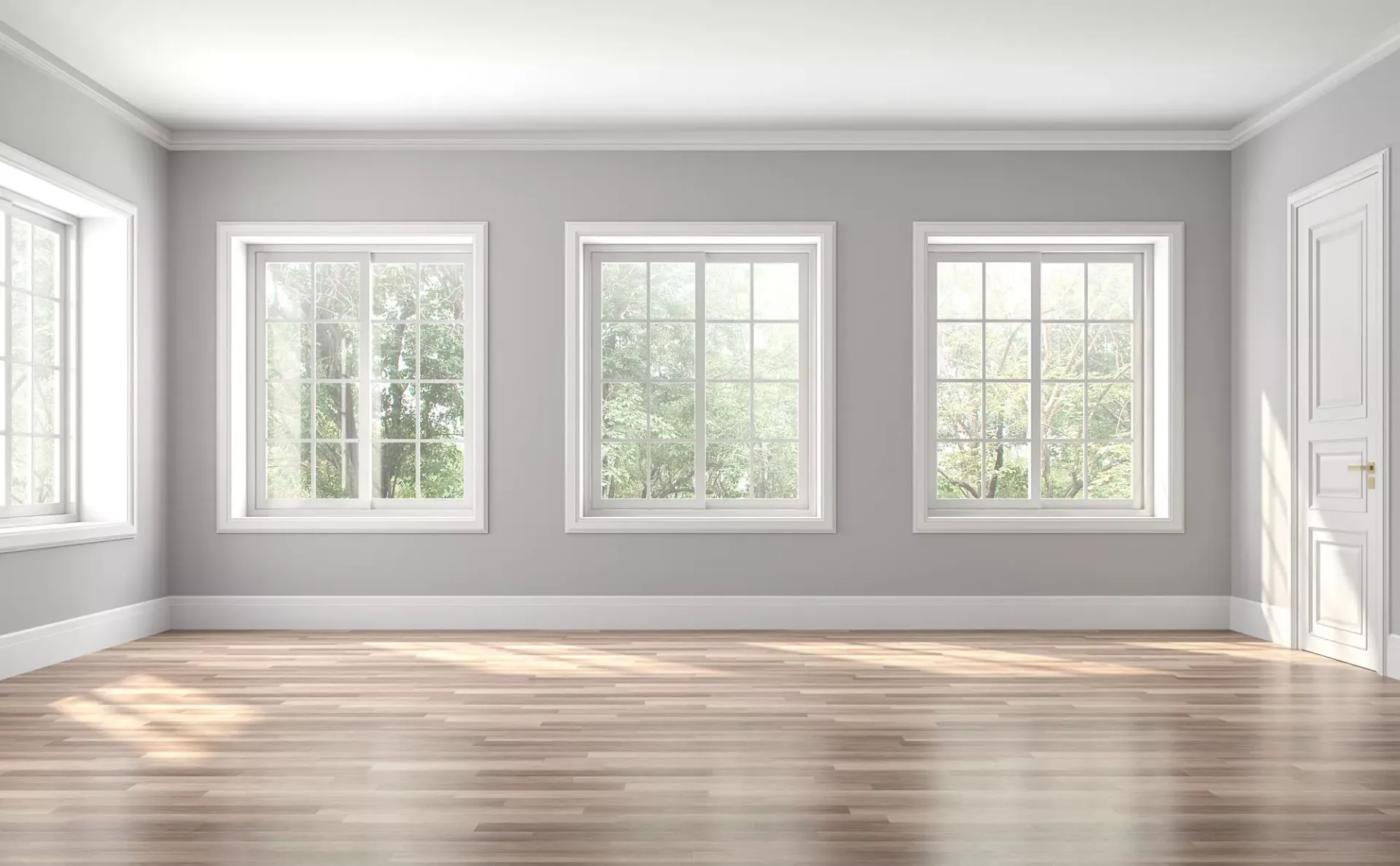 Empty room with three windows and a door, light gray walls, white trim, wooden floor.