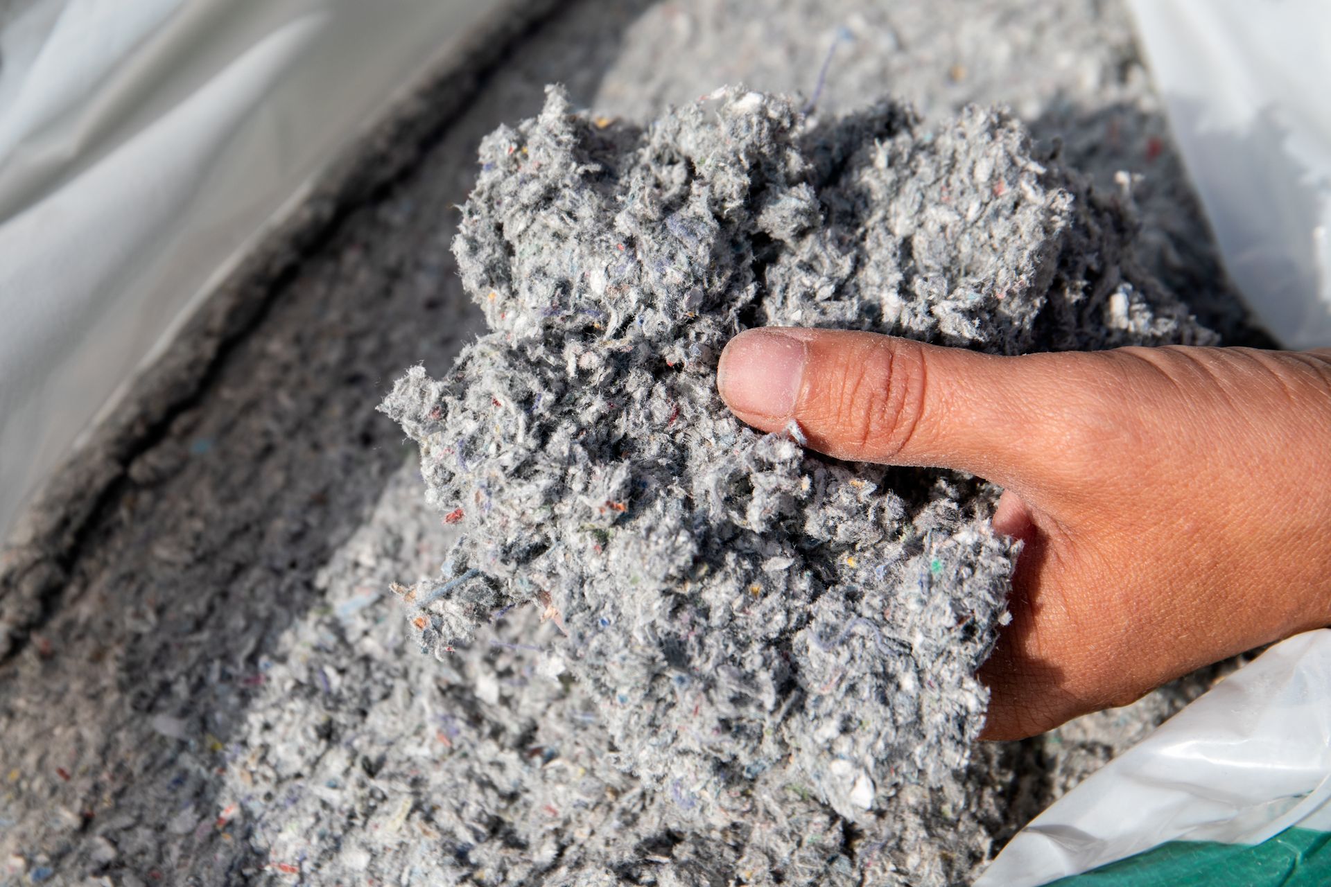 A hand holding a clump of cellulose insulation.