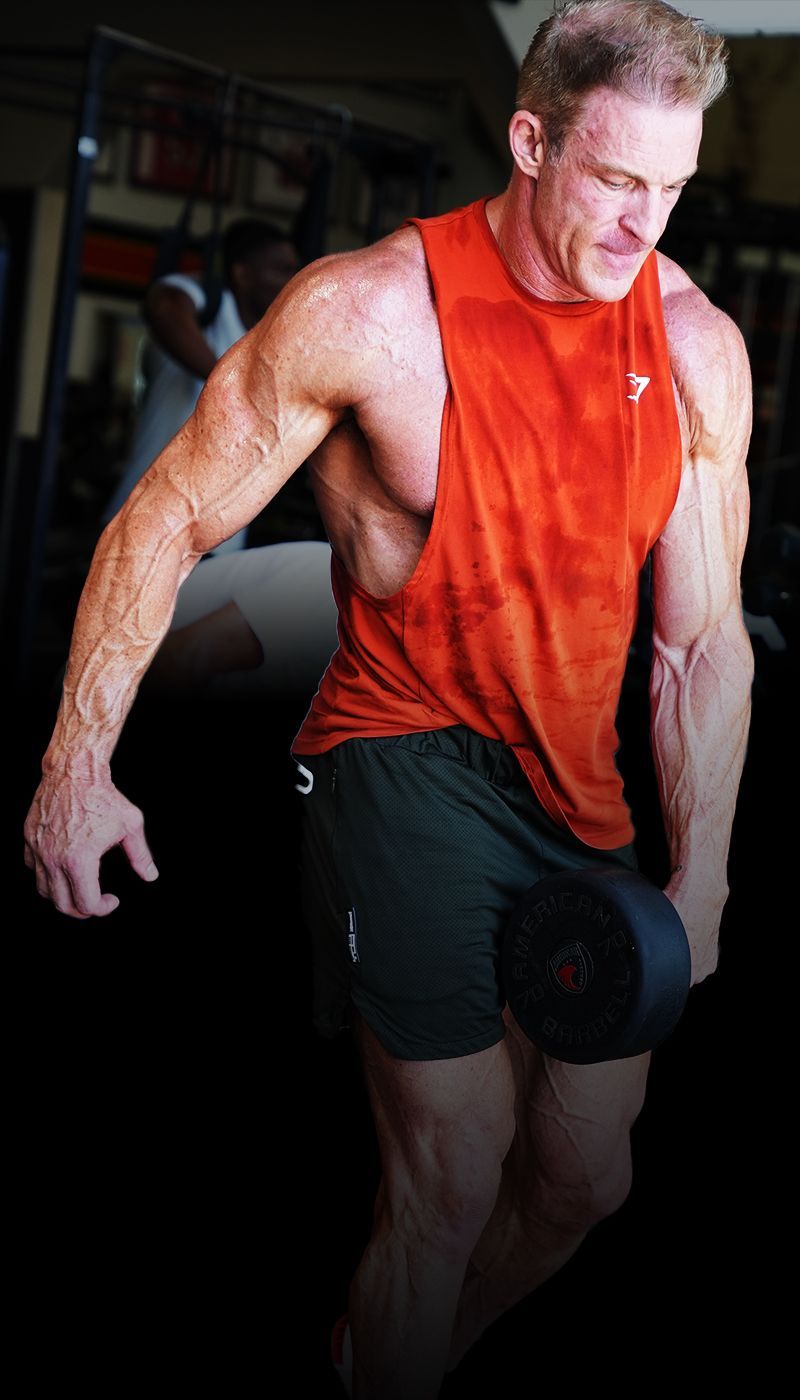Ron Matthews  in an orange tank top is lifting a dumbbell