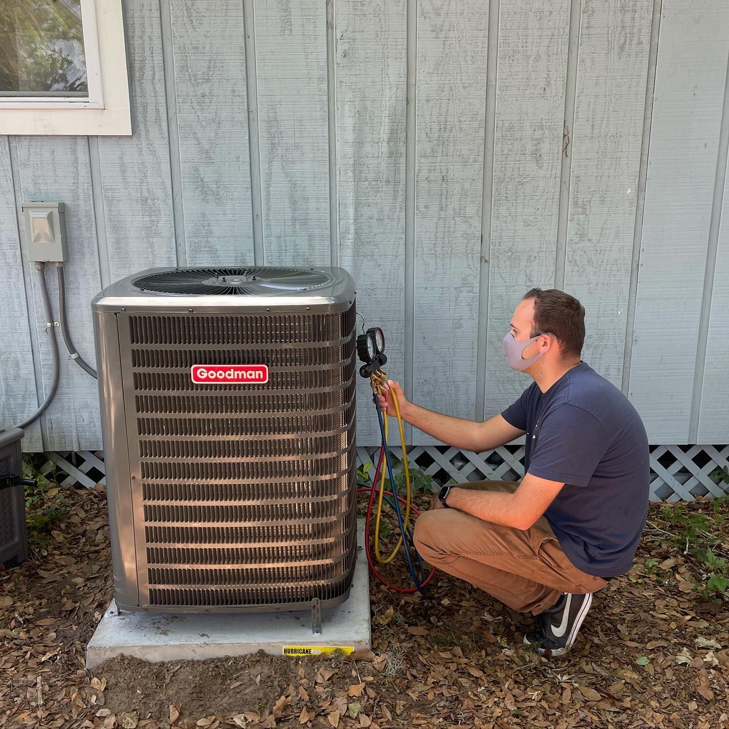 A man is working on an air conditioner outside of a house.