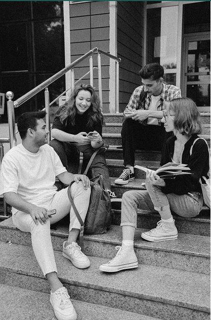 A group of young people are sitting on the steps of a building.