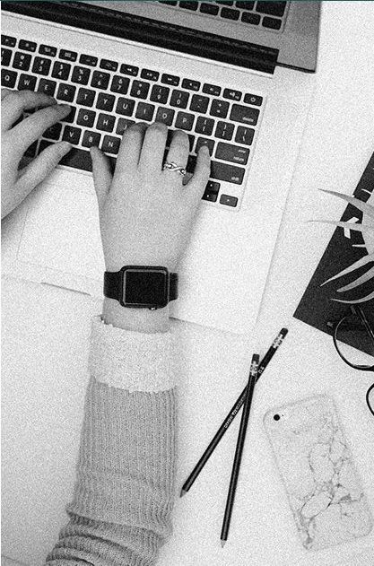 A person is typing on a laptop computer while wearing a watch.