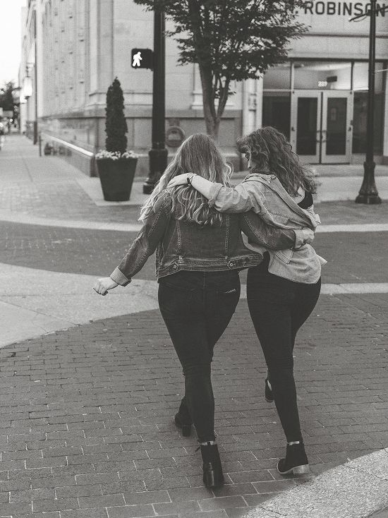 A black and white photo of two women hugging in front of a building that says robinsons