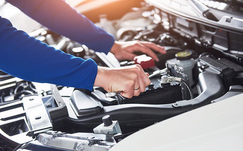 A mechanic is working on the engine of a car.